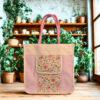 A beige and pink canvas tote bag with pink floral print detailing