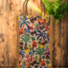 A medium-sized rectangular jute bag featuring a vibrant and detailed tropical print with palm trees, birds, and flowers.