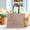 Textured jute tote bag with blue handles and a natural beige body.