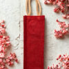 Plain red jute bottle bag with sturdy cotton rope handles, ideal for single bottle gifting or retail use.