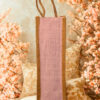Eco-friendly jute bottle bag with soft pink herringbone panel and natural jute handles.