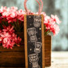 Jute bottle bag with a black fabric panel featuring traditional djembe drum prints and sturdy red-and-white braided rope handles.