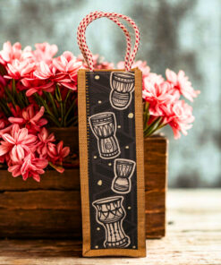 Jute bottle bag with a black fabric panel featuring traditional djembe drum prints and sturdy red-and-white braided rope handles.