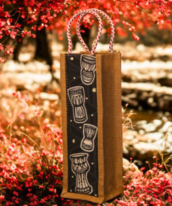 Jute bottle bag with a black fabric panel featuring traditional djembe drum prints and sturdy red-and-white braided rope handles.