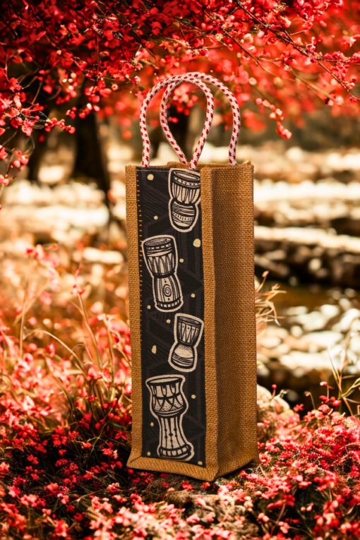 Jute bottle bag with a black fabric panel featuring traditional djembe drum prints and sturdy red-and-white braided rope handles.