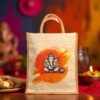 A jute tote bag with an illustration of Lord Ganesha sitting in front of an orange and yellow brushstroke background