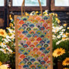 A medium-sized rectangular jute bag featuring a vibrant and colorful repeating pattern of overlapping semi-circles resembling fish scales or waves.