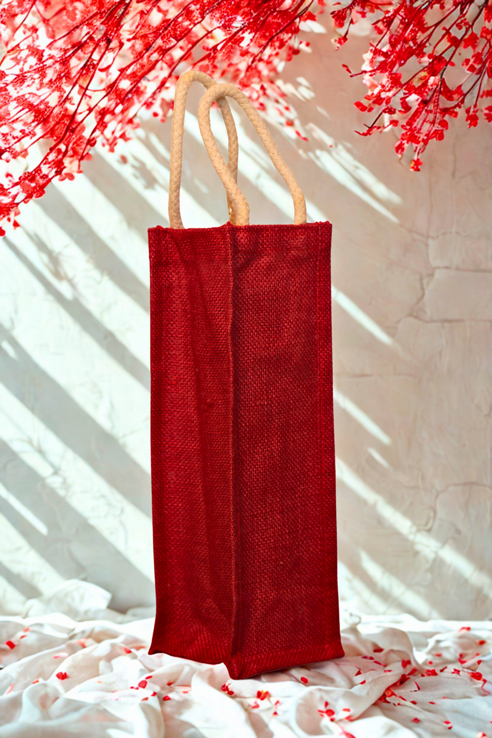 6642f05a-4f27-4ad6-82ae-ede7723daf0b Plain red jute bottle bag with sturdy cotton rope handles, ideal for single bottle gifting or retail use.
