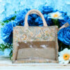 A small canvas tote bag with floral paisley print and a transparent plastic front panel