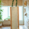 Tall jute bottle bag with herringbone front panel and green braided handles.