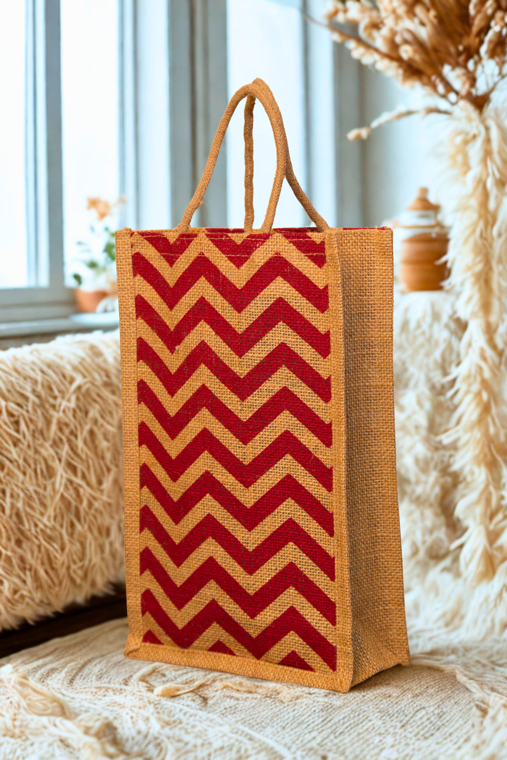 7c484528-6cc7-43cc-b633-23195eac71b8 A medium-sized rectangular jute bag with a bold, repeating red and natural jute chevron (zigzag) pattern.
