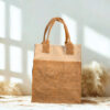 A two-tone jute and cotton tote bag standing upright on a gray cloth