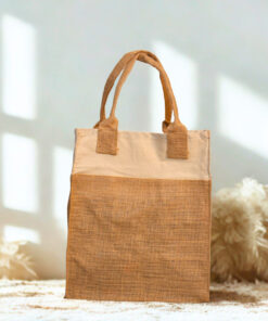 A two-tone jute and cotton tote bag standing upright on a gray cloth