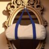 Natural canvas cylindrical duffle bag with royal blue handles and straps