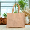 Structured woven jute handbag with rounded rope handles and a boxy rectangular shape in natural beige tone.