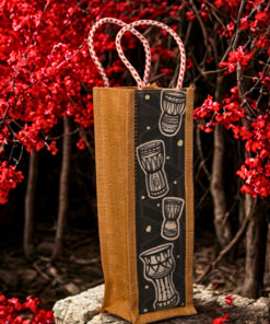 Jute bottle bag with a black fabric panel featuring traditional djembe drum prints and sturdy red-and-white braided rope handles.