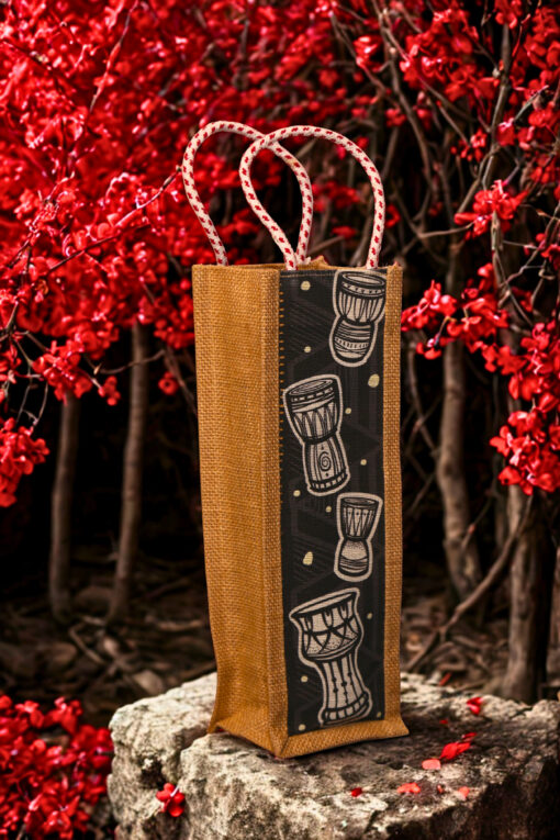 Jute bottle bag with a black fabric panel featuring traditional djembe drum prints and sturdy red-and-white braided rope handles.