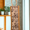 Eco-friendly jute bottle bag with monochrome black and brown floral print and soft white rope handle.