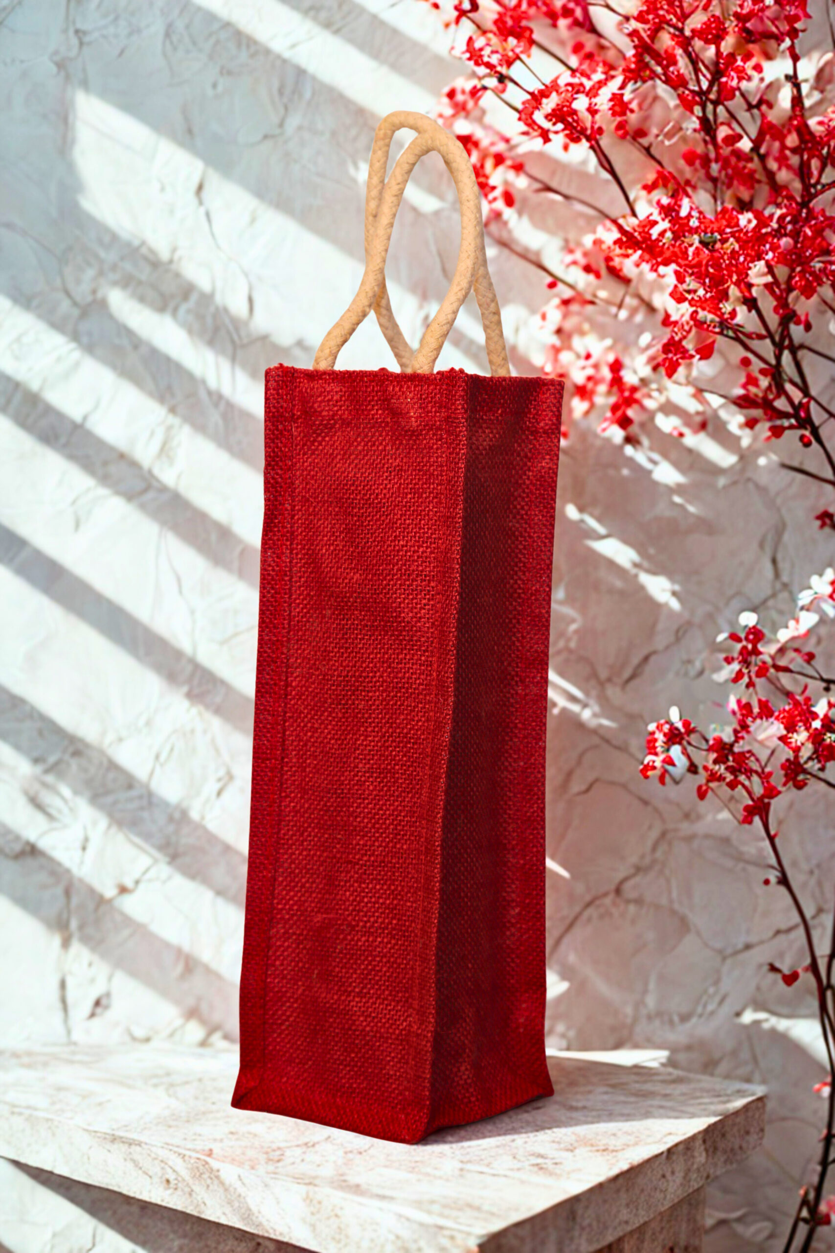 ebade18f-274f-423e-a9fb-d7a5d801fee8 Plain red jute bottle bag with sturdy cotton rope handles, ideal for single bottle gifting or retail use.