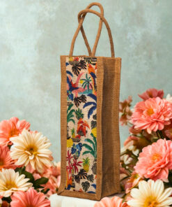 A tall, narrow jute bag with a colorful, whimsical print featuring tropical birds, flowers, and foliage.