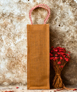 Jute bottle bag with a black fabric panel featuring traditional djembe drum prints and sturdy red-and-white braided rope handles.
