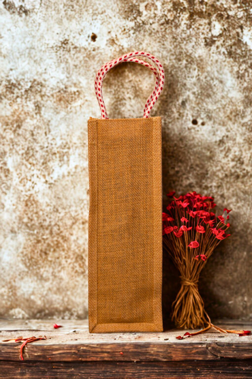 Jute bottle bag with a black fabric panel featuring traditional djembe drum prints and sturdy red-and-white braided rope handles.