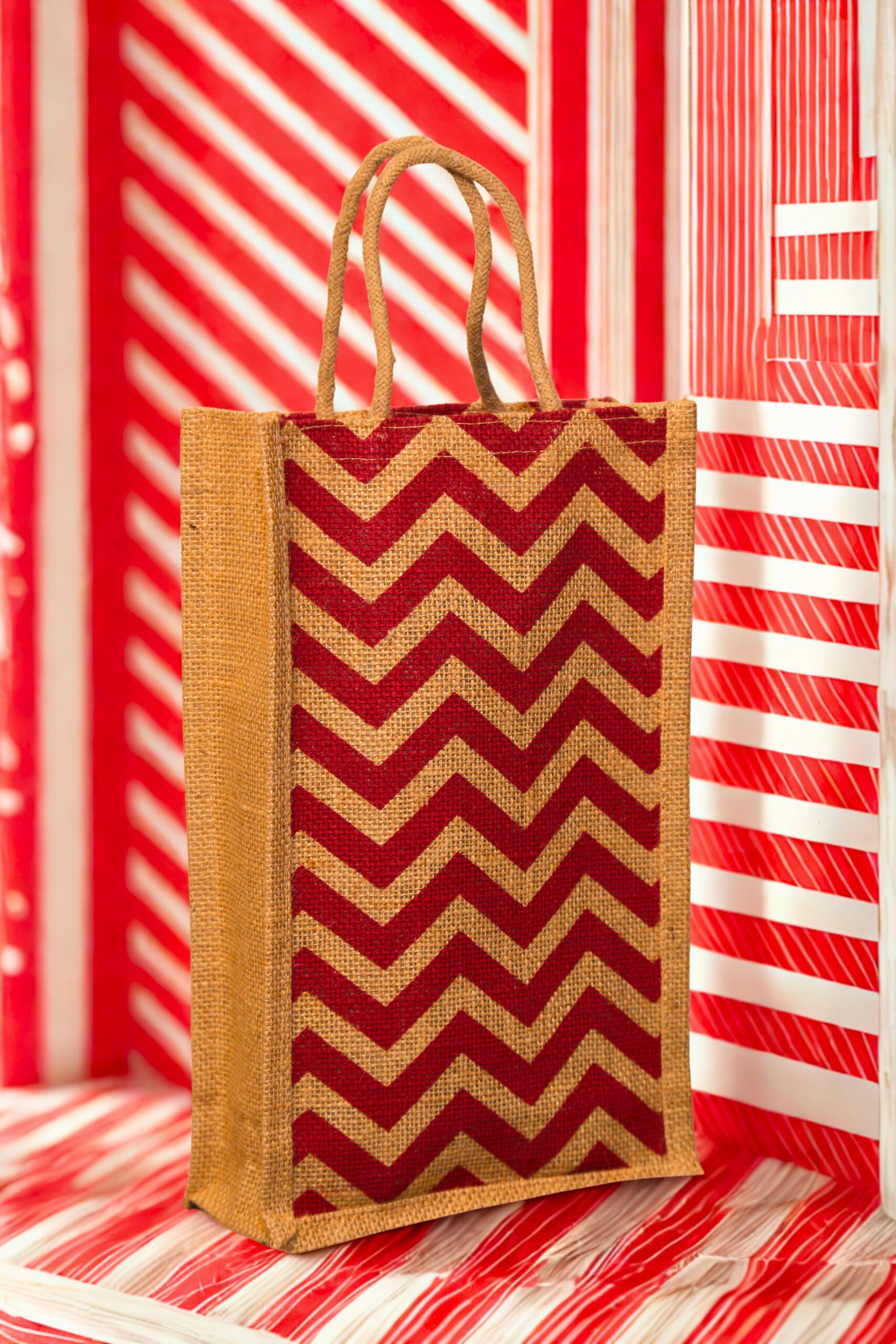 fd491b0e-a5c5-429a-b0d5-bce421563fce A medium-sized rectangular jute bag with a bold, repeating red and natural jute chevron (zigzag) pattern.