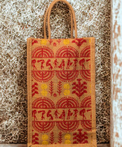 A medium-sized rectangular jute bag featuring a traditional Indian folk art print in red and yellow on a natural jute background.